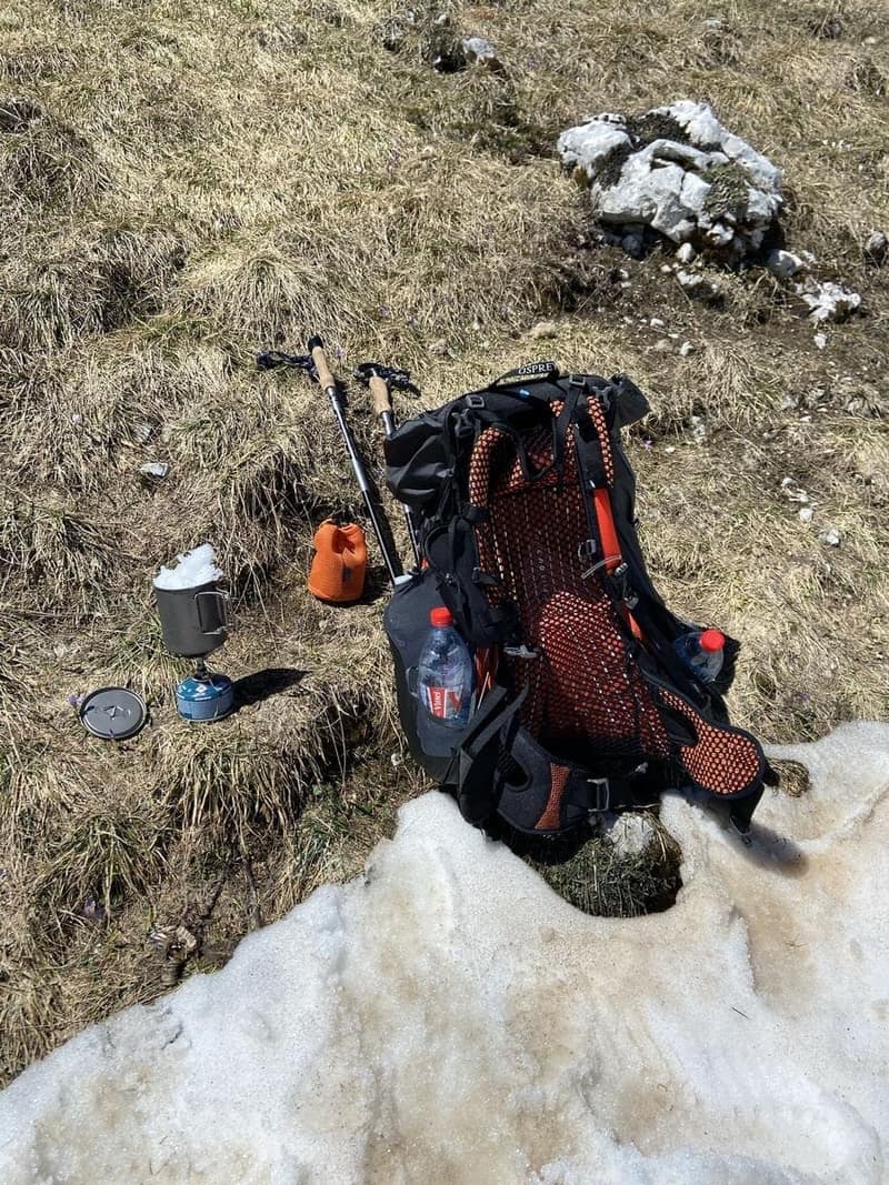 Sac à dos de randonnée posé dans l'herbe avec bâtons et réchaud